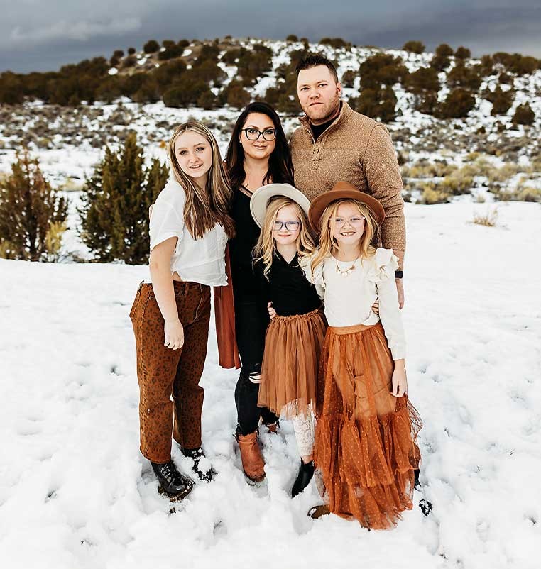 A family with young children posing for a photo by a snowy hillside